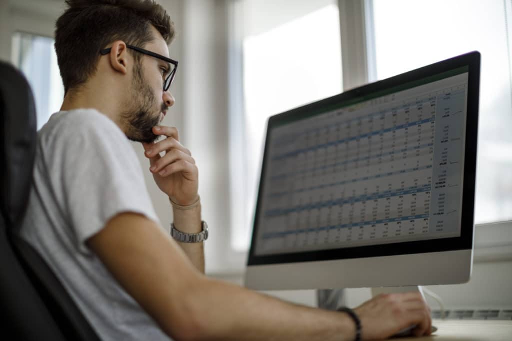 Young man using Pivot Tables on his computer at home